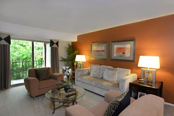 a living room with an orange accent wall and a gray couch at Liberty Gardens Apartments, Maryland, 21244